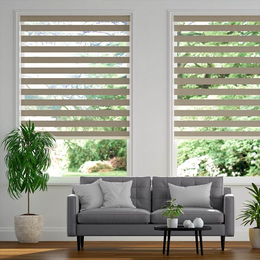 Light beige zebra blinds in a bright living room with green outdoor view