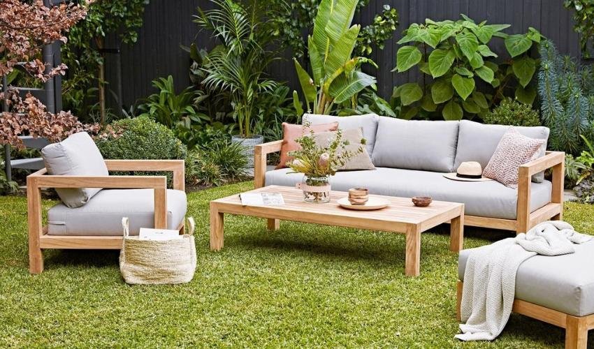 Light wood outdoor sofa surrounded by tropical greenery