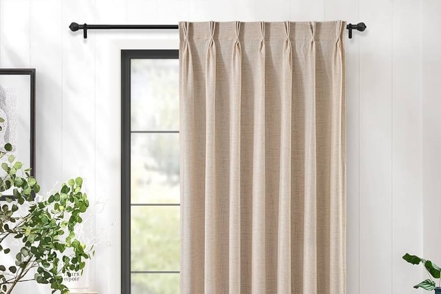 Blush pink blackout curtains on a black curtain rod.