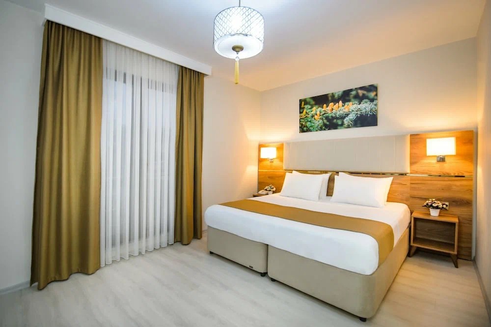Hotel room with double bed, armchairs, and balcony view