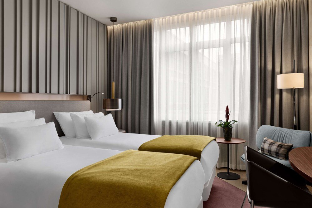 Single bed in a cozy room with neutral tones and curtain backdrop