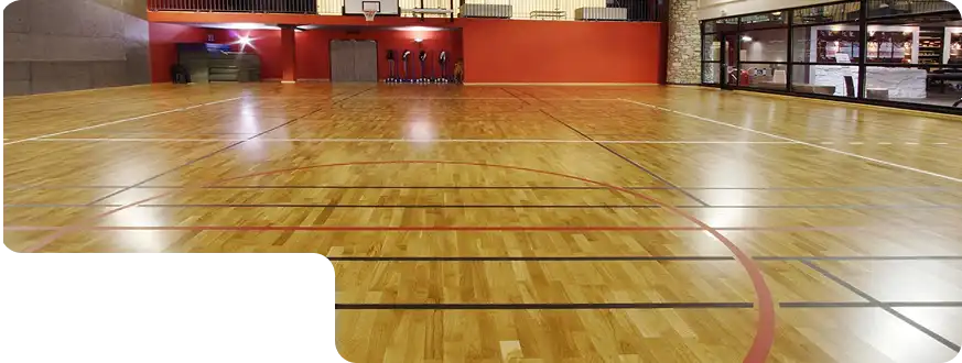 Professional-grade sports court with polished wooden flooring and red accent wall.