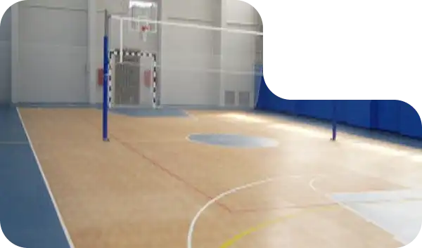 Indoor multi-purpose court with volleyball net and tan sports flooring marked for various games.