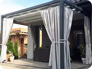Gray all-weather outdoor curtains on a patio gazebo, tied back for open-air lounging.