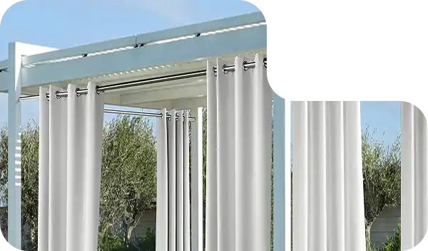 Modern pergola with white all-weather outdoor curtains and greenery in the background.