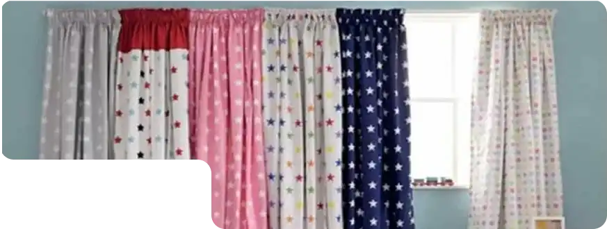 Set of multicolored kids’ curtains with star and polka dot prints on a blue wall