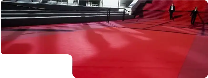 Wide red carpet on outdoor staircase with two people in black suits