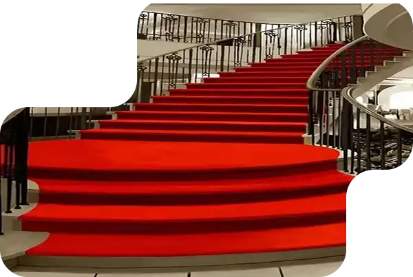 Red carpet on a spiral staircase with black railing in a modern setting