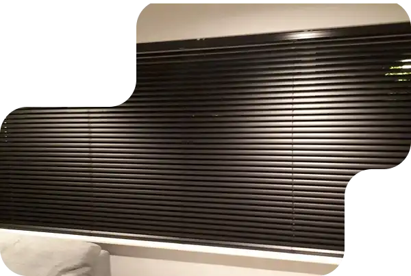 Black horizontal venetian blinds fully closed in a modern interior space