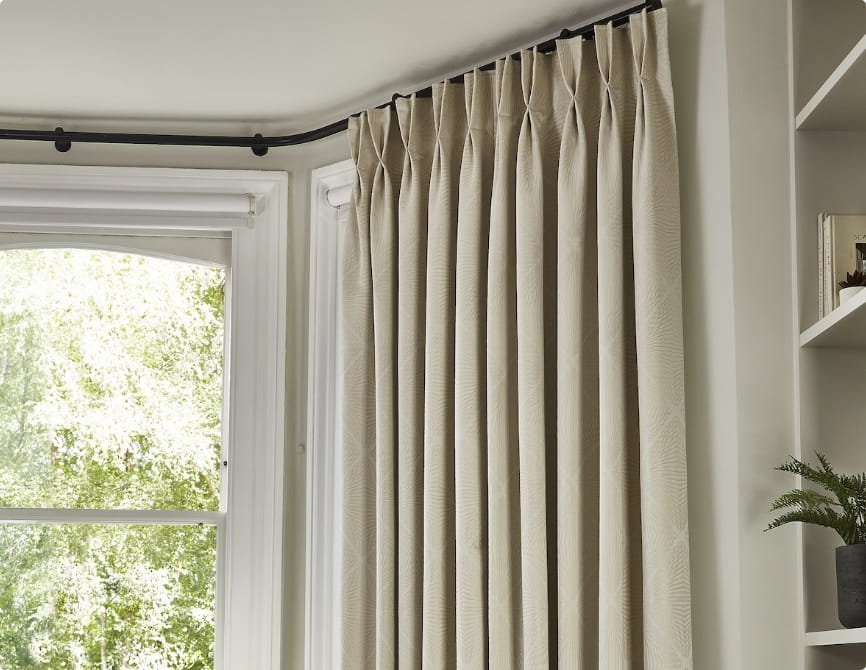 Off-white curtains installed on a ceiling-mounted curtain rod.
