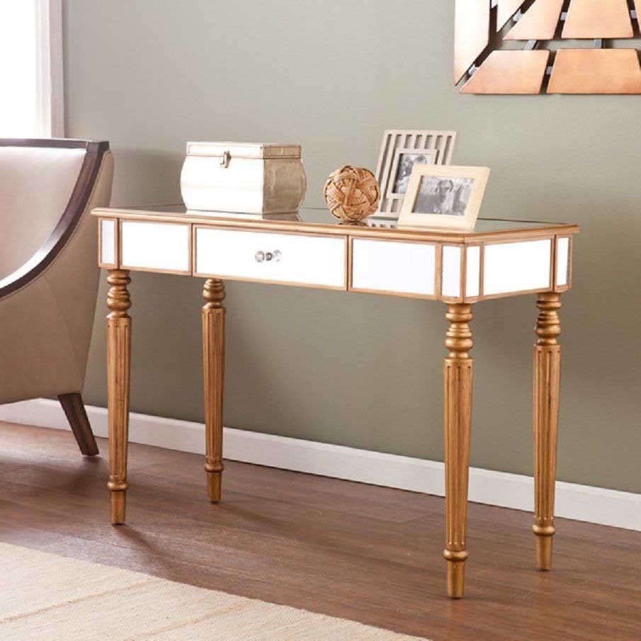 White console table with gold legs and two drawers, styled with photo frames and flowers.