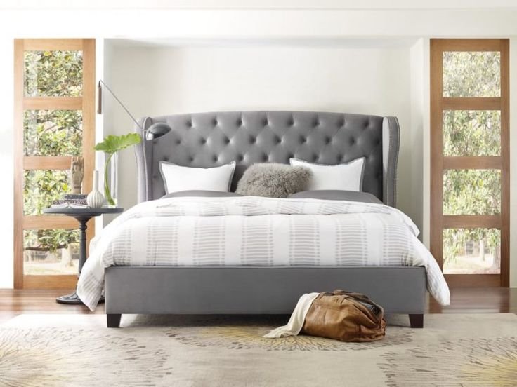 Upholstered bed with high wingback headboard in soft beige fabric.