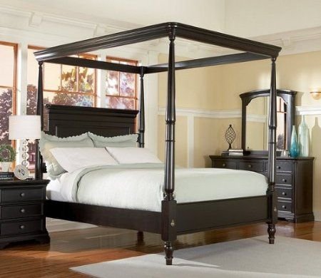 Classic four-poster canopy bed with white curtains and stylish headboard.