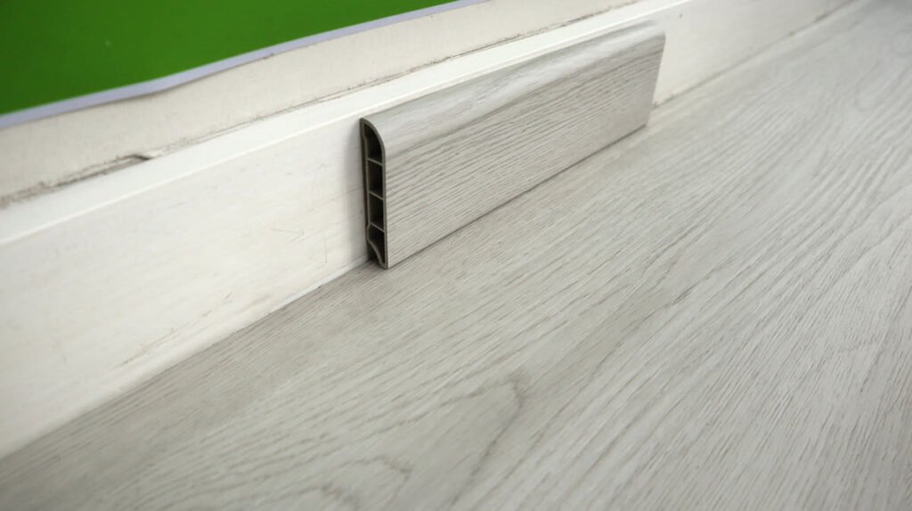 Grey SPC skirting with sleek profile for wall finishing.