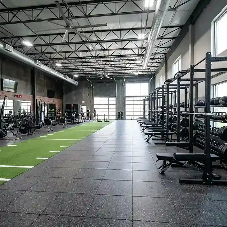 Gym with weight racks and dark rubber tile flooring beside a green turf lane
